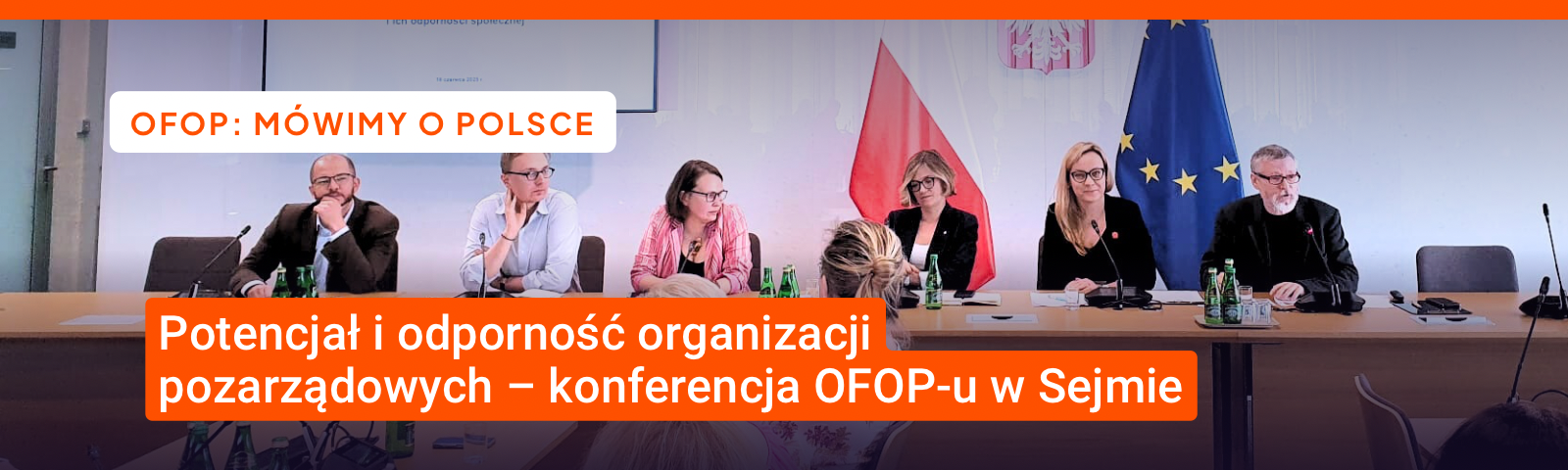 6 osób w oficjalnych strojach siedzi po jednej stronie długiego stołu przodem do widza, w tle flagi Polski i Unii Europejskiej. Tekst: OFOP. Mówimy o Polce. Potencjał i odporność organizacji pozarządowych – konferencja OFOP-u w Sejmie. 
